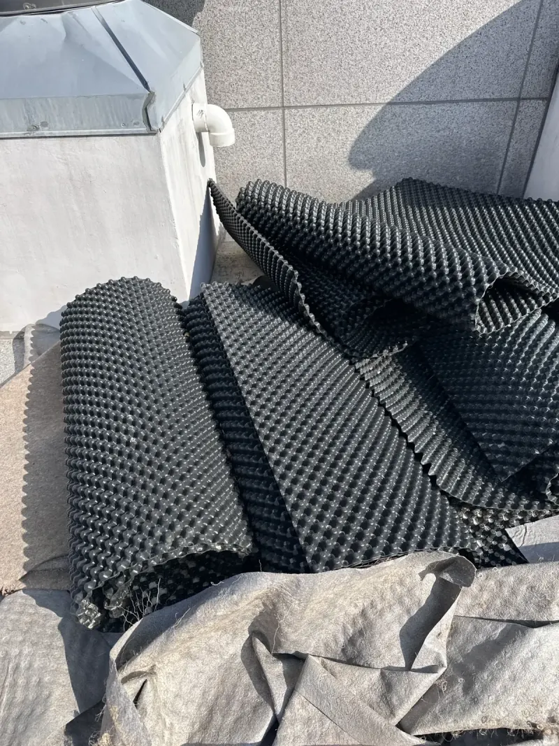 옥상에 쌓아 둔 돌출 배수판 롤과 부직포 자재